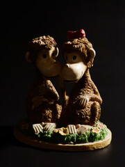 Two Cute Monkey Figurines Kissing Dark Background