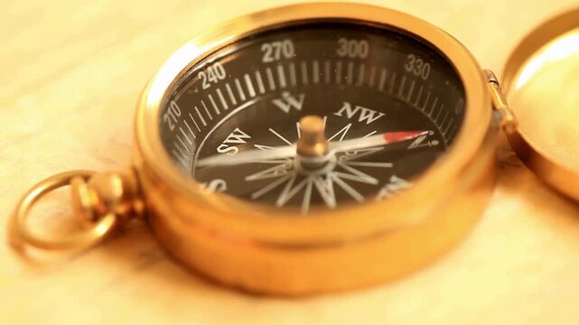 Retro styled golden compass and old white nautical chart close-up. Close-up of an old retro vintage style compass. Travel geography navigation concept. Adventure, discovery, transport theme concept.