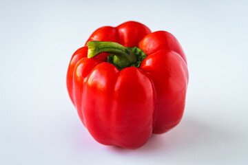 Close-up shot of a single fresh red bell pepper, showcasing its glossy skin and crisp green stem against a simple background.