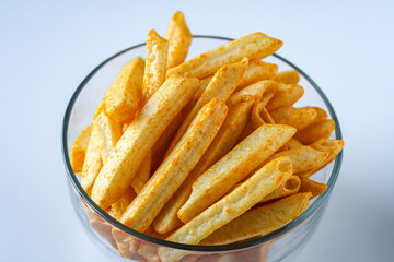 A close-up shot of a clear glass bowl filled with golden yellow crispy cheese sticks, a snack similar to the shape of French fries and are generously seasoned. Captured against a clean background.