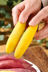 Fresh Small Yellow Fingerling Potatoes Being Held Over Cutting Board in Kitchen
