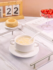 Fresh corn kernel soup with polenta bread and cherry tomatoes on white serving tray