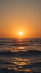 Obraz premium Golden sunset over the ocean with gentle waves reflecting the warm light, creating a serene and tranquil atmosphere