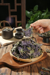 Dried Purple Shiso Leaves in Bamboo Basket with Traditional Tea Set on Wooden Table