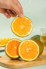 Fresh Orange Slices on Wooden Board - Hand Holding Citrus Fruit for Healthy Nutrition and Cooking