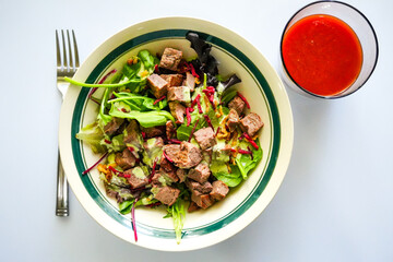 Refreshing cold steak salad, loaded with greens, shredded beets, and creamy dressing—served alongside a bold glass of fresh tomato juice for a nutrient-rich bite.