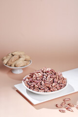 Colorful Mixed Nuts and Grains in White Bowls on Pink Background - Healthy Food Ingredients
