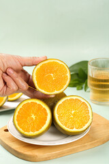 Fresh Orange Slices on Wooden Board - Hand Holding Citrus Fruit for Healthy Eating and Natural Nutrition Concept