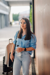 Businesswoman waiting with suitcase and water bottle at airport