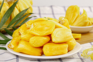 Fresh Golden Jackfruit Segments on White Plate with Tropical Leaves - Exotic Fruit Display
