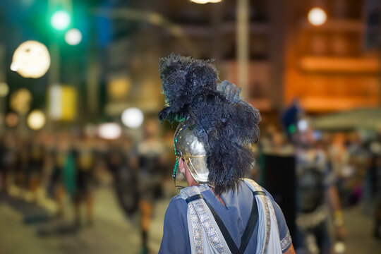A person from behind, wearing a Roman helmet, parading through the streets of Cartagena on its main day of festivities