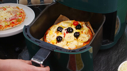 Homemade Pizza with Cheese and Olives Cooking in Air Fryer Kitchen Appliance