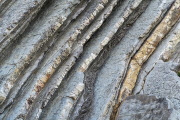 Layered rocks, flysch texture background. Sedimentary rock, striations stone pattern