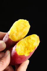 Fresh Sweet Potato Cut in Half Showing Yellow Flesh in Hands on Black Background