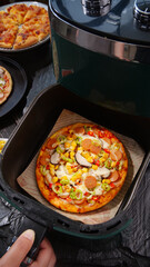 Fresh homemade pizza with bacon, cheese and vegetables cooking in kitchen appliance
