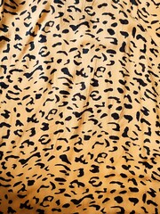 The pattern and background of the yellow fabric with black dots resembles leopard skin.