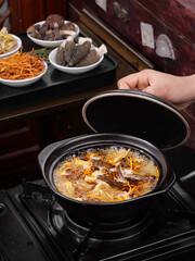 Traditional Yunnan Mushroom Soup with Colorful Ingredients and Buns in Clay Pot