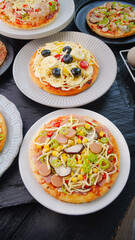 Assorted Italian Pizzas with Cheese and Fresh Toppings on White Plates