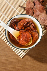 Yunnan Dried Red Porcini Mushrooms in Hot Broth with Wooden Spoon - Traditional Asian Cooking Ingredients