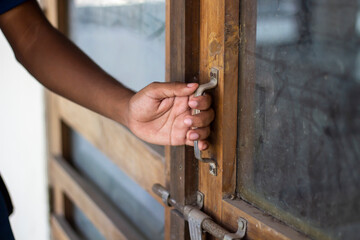 Hand opening a wooden door with glass pane