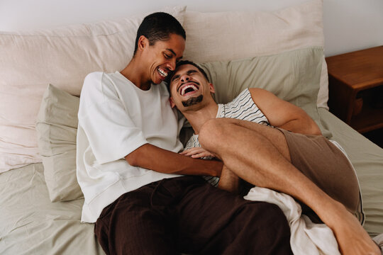 Happy couple sharing laughter and relaxation on a cozy bed indoors