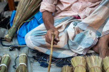 Man sitting and making brooms from natural materials