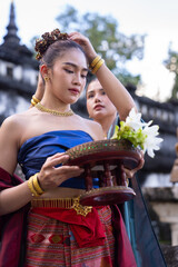 Traditional Thai dancers in vibrant costumes hold floral offering, showcasing cultural heritage and elegance