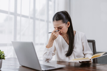 Woman feeling tired and stressed while working at desk