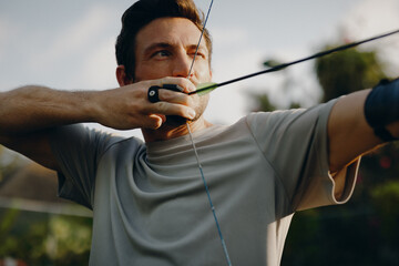 Skillful man practicing archery outdoors