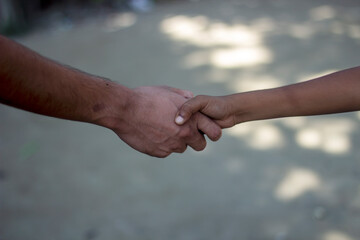 An adult hand holds a childs hand in a gesture of support