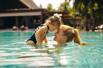 Mother and daughter sharing a loving moment at a resort pool