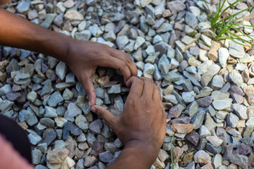 Hands forming a heart shape on a bed of small stones