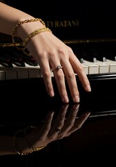 Elegant hand with gold bracelets and ring reflected on a black piano