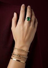 Elegant hand with jewelry displaying gemstone ring and bracelets against dark backdrop