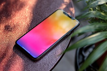 Modern Smartphone Aesthetic: A sleek smartphone rests elegantly on a textured surface, showcasing a vibrant display, blending technology with a touch of nature.