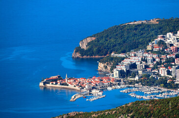 Naklejka premium Aerial view of picturesque scenery - old town and Adriatic sea, Budva, Montenegro. Bird's-eye view of beautiful scene with medieval houses and seascape. Topic of summer vacation, travel, cruise, tour