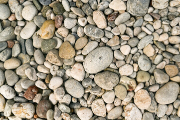 Assortment of rounded pebbles and small stones with natural textures. Coastal surface with weathered stones in organic arrangement, radiating calm and pebbles-rich pattern. abstract background