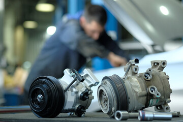 Garage. The service center. Auto parts. An auto mechanic is preparing to replace the radiator compressor.In the foreground on the desktop are a new compressor and an old faulty compressor.