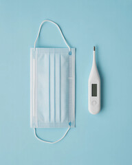 Medical Mask and Thermometer on Blue Minimalist Background