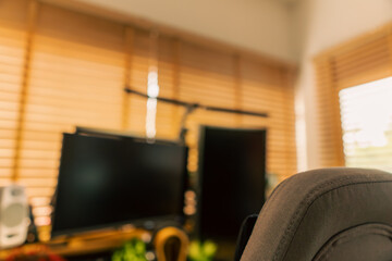 Cozy vintage desk setup featuring warm lighting, monitor, keyboard, gaming chair and gadgets in a studio workspace. Perfect background for productivity, lifestyle and workstation themes.