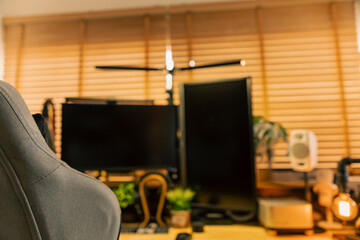 Cozy vintage desk setup featuring warm lighting, monitor, keyboard, gaming chair and gadgets in a studio workspace. Perfect background for productivity, lifestyle and workstation themes.