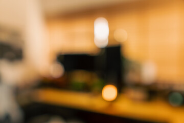 Cozy vintage desk setup featuring warm lighting, monitor, keyboard, gaming chair and gadgets in a studio workspace. Perfect background for productivity, lifestyle and workstation themes.