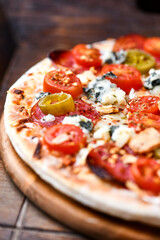 Pizza with salami, jalapeno pepper, cherry tomatoes and mozzarella cheese. Soft focus.	