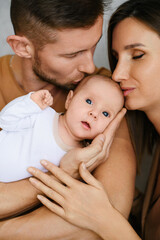 Parents Holding Baby And Kissing Gently
