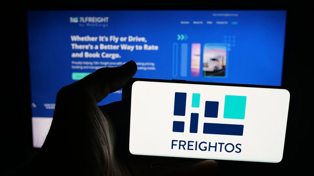 Stuttgart, Germany - 09-25-2025: Person holding mobile phone with logo of freight booking company Freightos Ltd. on screen in front of web page. Focus on phone display.