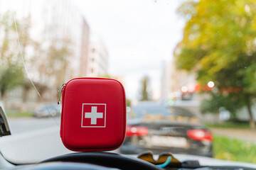 A small, compact red first aid kit is prominently positioned on the vehicles dashboard, ensuring...
