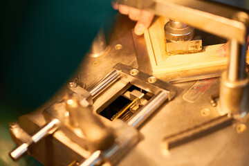 Man operating industrial machine while assembling wooden frame, hands adjusting wood piece under metal press, close up of manufacturing process in workshop