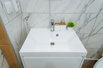 A stylish bathroom that features essential fixtures such as a sleek sink, a modern toilet, and elegant marble tiles adorning the floor and walls, creating a sophisticated atmosphere