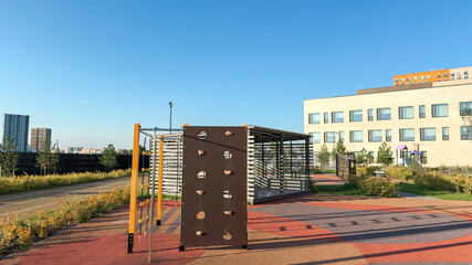 Modern schoolyard with outdoor playground, climbing wall and sports area. Contemporary education environment with safe facilities and urban landscape.