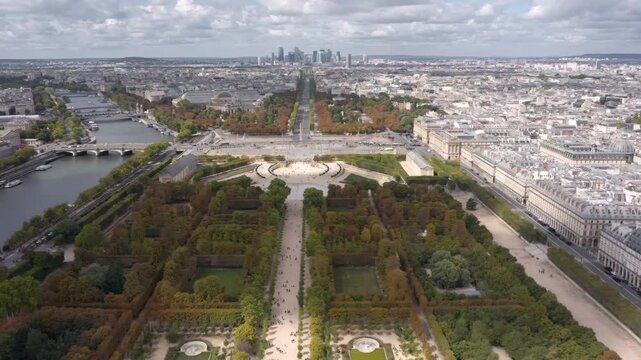 A breathtaking aerial drone view over Paris captures the Tuileries Garden, the Seine River, and the historic city skyline stretching into the horizon.